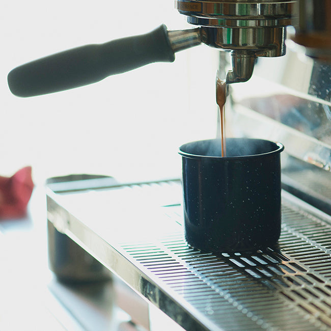 Espresso pouring from portafilter on espresso machine into mug 